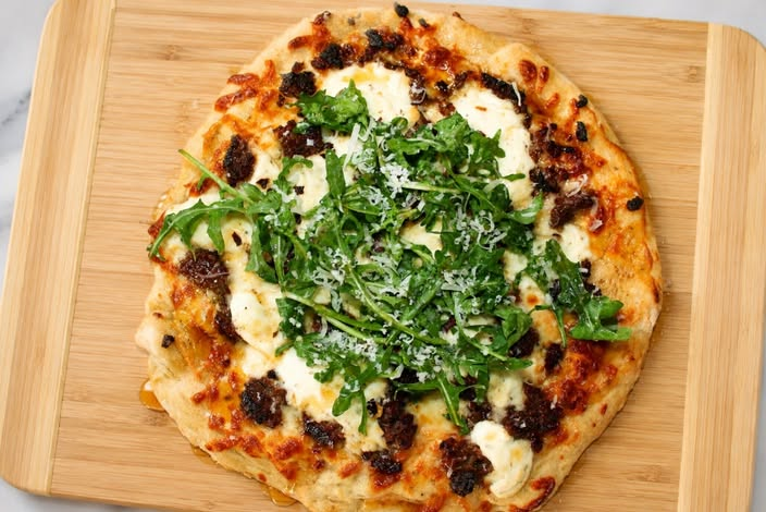 Hot honey ricotta sausage pizza topped with arugula